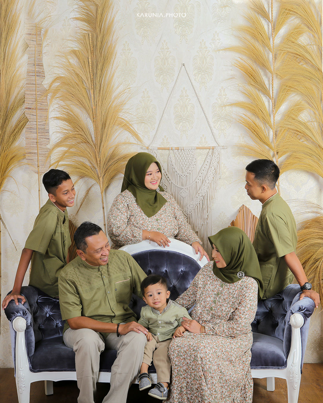 Three siblings sitting on wooden steps in coordinating outfits with genuine smiles and relaxed poses